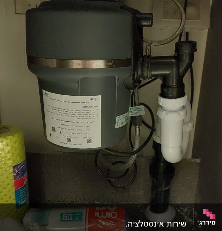 מכשיר טוחן אשפה מתחת לכיור עם צינורות חיבור